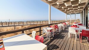 Een restaurant aan het strand met terras en uitzicht op de oceaan.