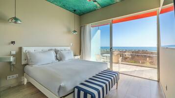 Un dormitorio con una cama, un banco, un techo de diseño único y un balcón con vistas al mar.