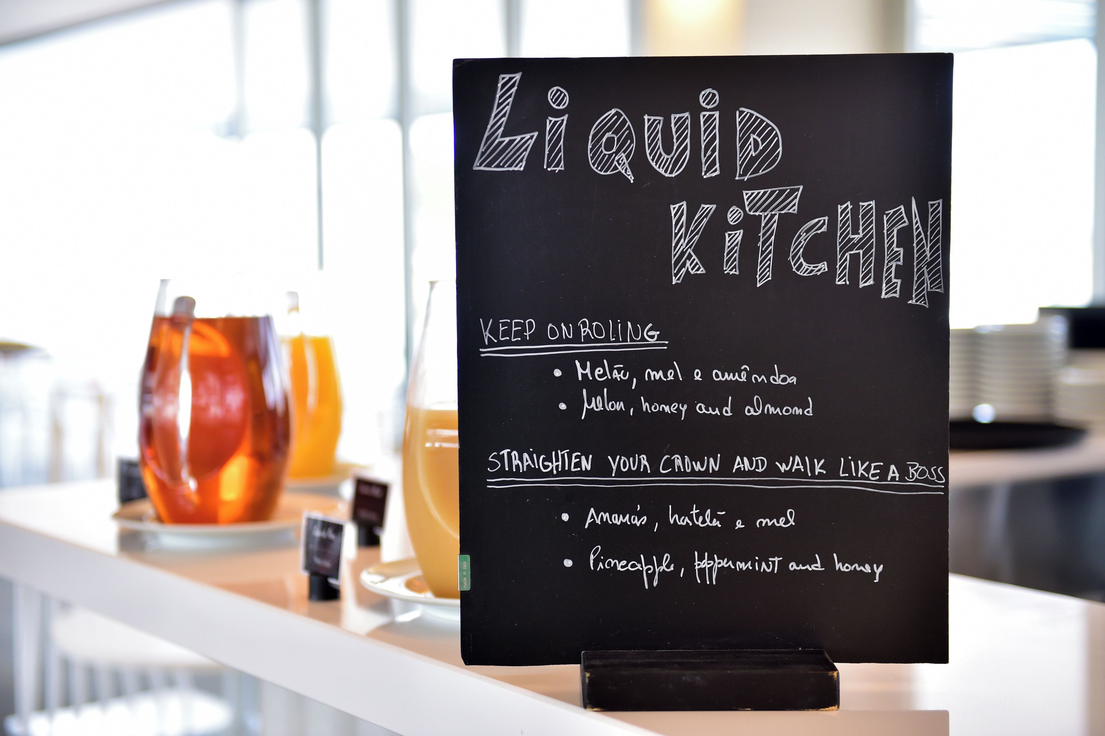 Un menú en una pizarra con el título 'Liquid Kitchen' que enumera ingredientes como melón, miel y almendras.