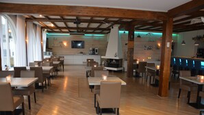 Een restaurant met houten vloeren, tafels, stoelen, een bar en een open haard.
