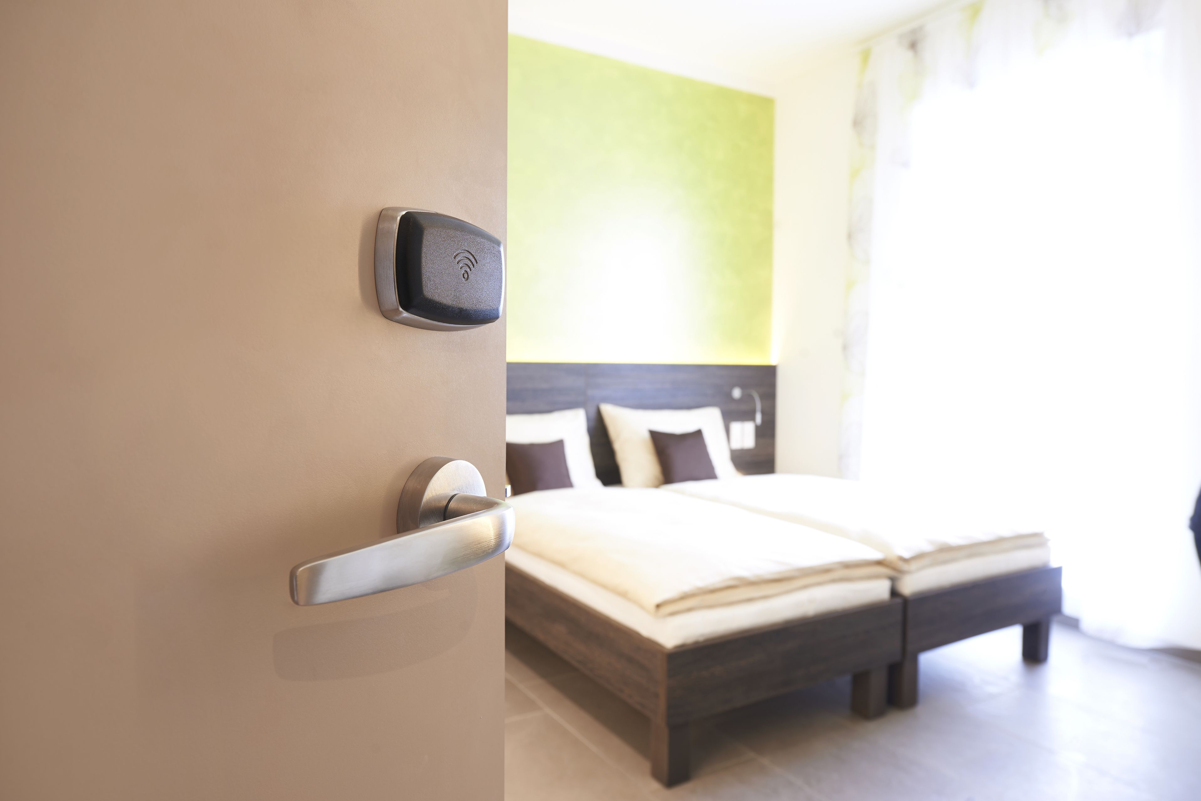 A modern hotel room with a bed, a bedside table, and a wall-mounted control panel.