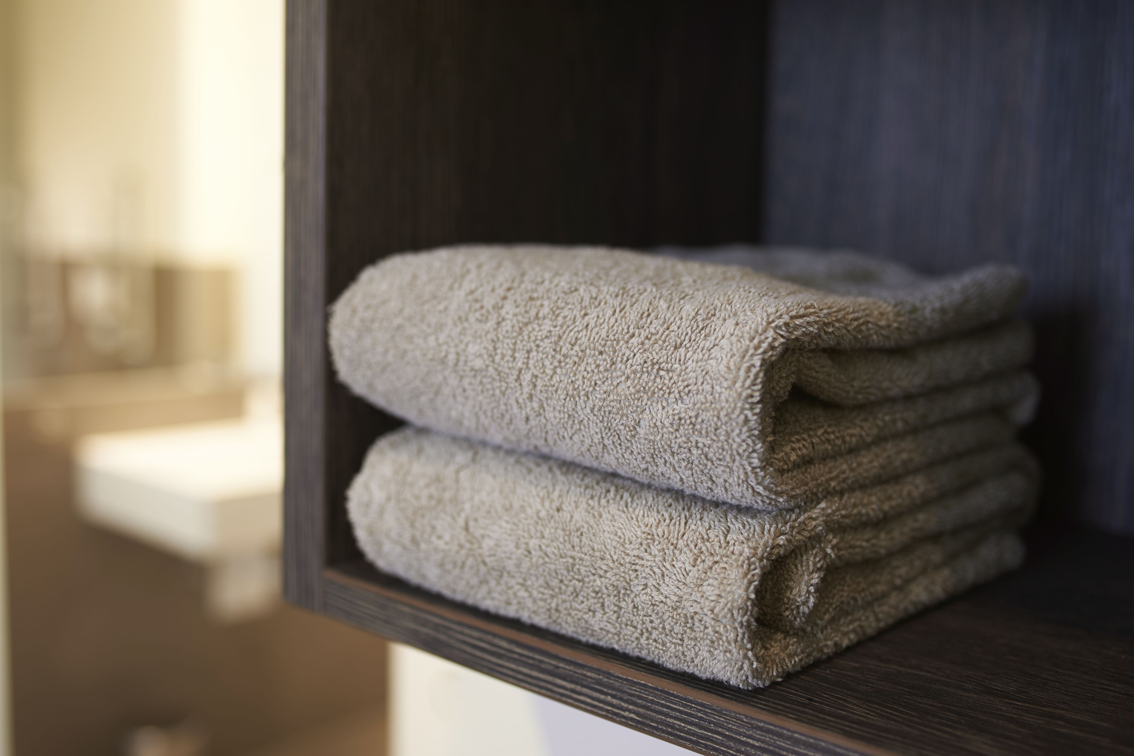 A stack of folded towels on a wooden shelf.