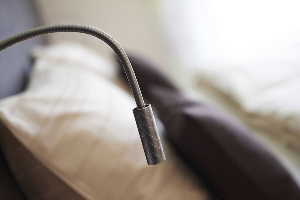 A close-up of a metallic, textured object, possibly a part of a bed or furniture, with a blurred background suggesting a domestic setting.