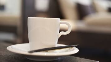 Una taza blanca sobre un plato con una cuchara sobre una mesa de madera.