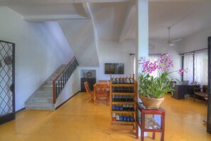 A spacious living area with a staircase, a wine rack, and a potted orchid. - PRASATs Boutique Hotel (Phnom Penh)