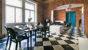 Un comedor con suelo de cuadros, paredes de ladrillo y ventanas amplias.