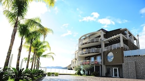 A multi-story hotel with balconies, a circular window, and a paved walkway.