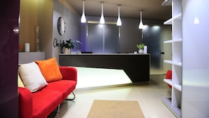 A modern reception area with a red sofa, a reception desk, and pendant lighting.