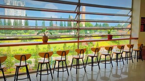 Una habitación con ventanas amplias, varias sillas y una planta en maceta.