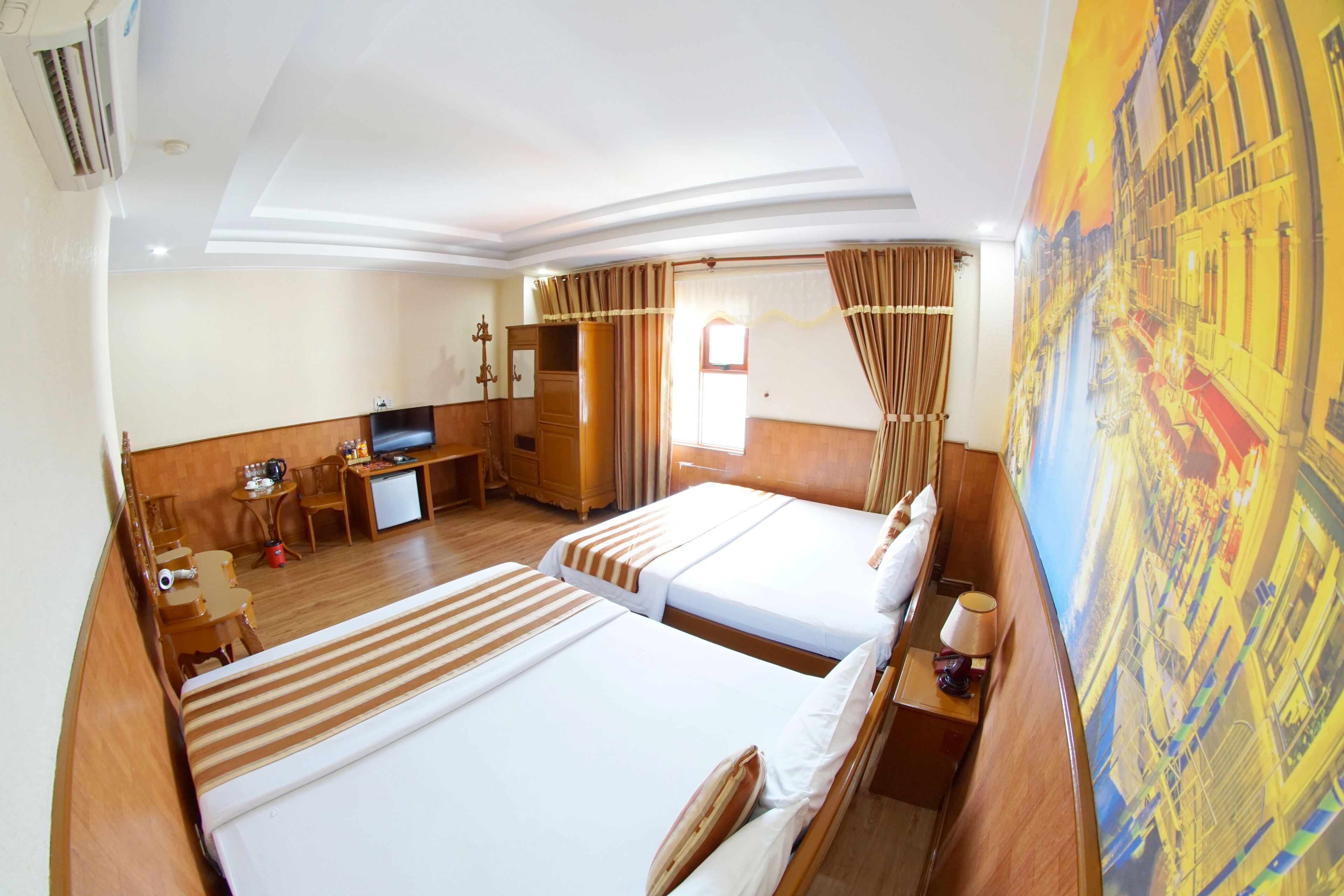 A hotel room with two beds, a desk, a TV, and a large window with curtains.