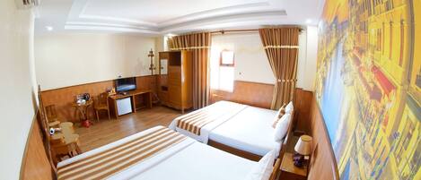 A hotel room with two beds, a desk, a TV, and a large window with curtains.