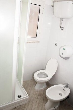 A bathroom with a toilet, bidet, and a shower area. - Hostel Melting Pot Rome (Rome)