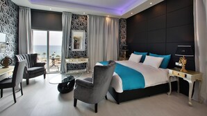 Una habitación de hotel moderna con una cama grande, un escritorio, una silla y vista al océano.