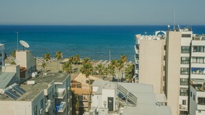Zona costera urbana con edificios, una playa y palmeras.
