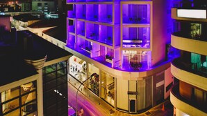 Un hotel de varios pisos con balcones iluminados y una entrada visible.