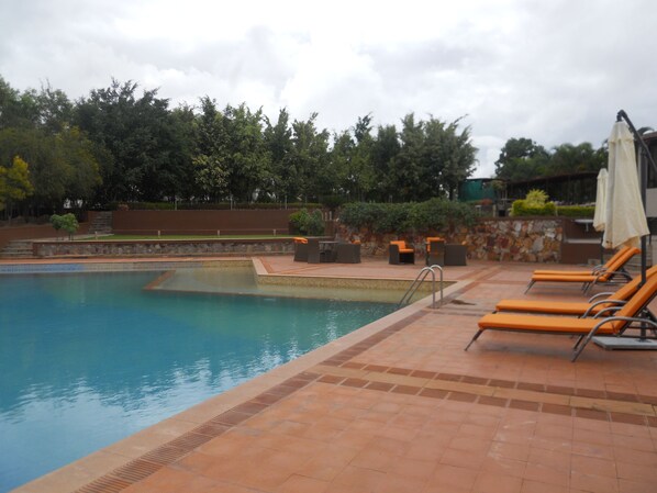 Piscina con sillas de descanso y un muro de piedra.