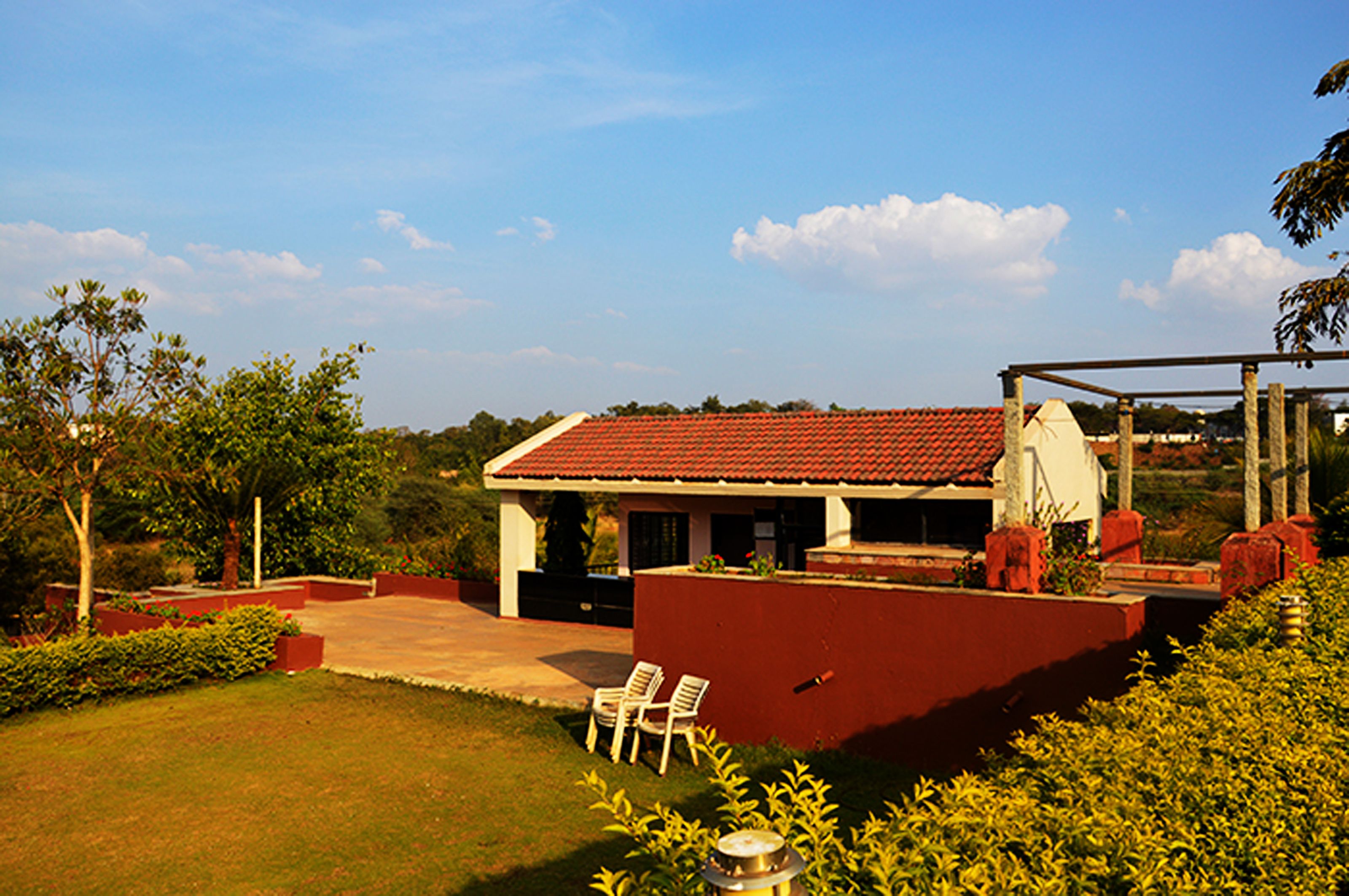 A house with a red roof, a patio with chairs, and a garden.