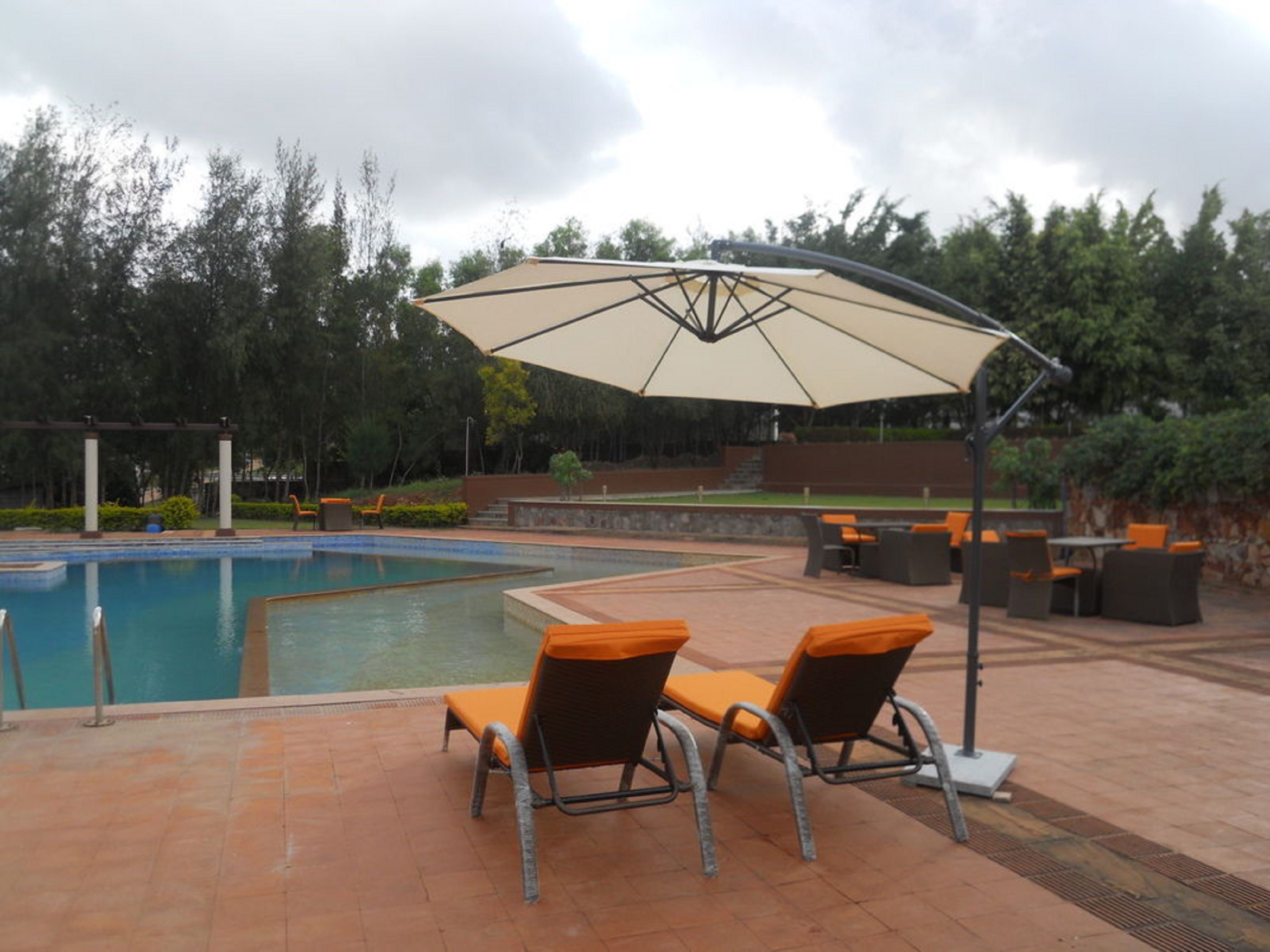 A poolside area with lounge chairs and a large umbrella.