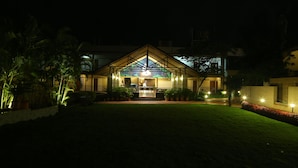 A well-lit building with a central entrance, surrounded by potted plants and a well-maintained lawn.