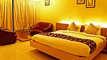 A hotel room with a large bed, a leather armchair, a glass coffee table, and a wooden headboard.