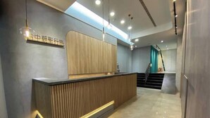 A reception desk with a wooden panel design, a lighted reception area, and a staircase leading to an upper floor. - Taichung Saint Hotel (Taichung)