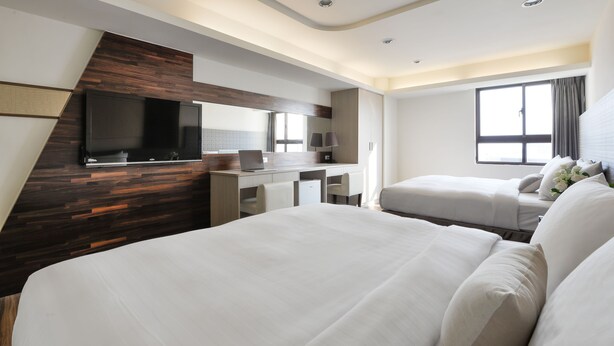 A modern hotel room with a large bed, a desk with a laptop, a flat-screen TV, and a window with curtains. - Taichung Saint Hotel (Taichung)