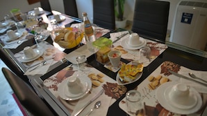 A dining table set with plates, cutlery, and various food items, indicating a meal setup in a hotel room. - B&B Col Moschin (Mestre)