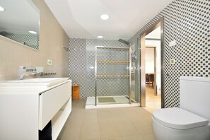 Uma casa de banho moderna com chuveiro, sanita e lavatório.
