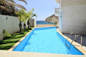 A swimming pool with a view of the ocean and a rocky cliff. - Atico Suite Ola Blanca (Finestrat)
