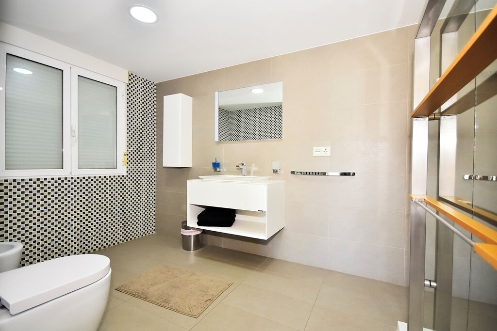 Une salle de bain moderne avec des toilettes, un lavabo et un miroir.