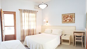 A hotel room with a large bed, a bedside table with a lamp, a desk with a chair, and a painting on the wall. - Studios & Apartments Efrosini (Dio-Olympos)