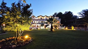 A multi-story hotel with a well-maintained lawn, outdoor seating, and a pool area. - Studios & Apartments Efrosini (Dio-Olympos)