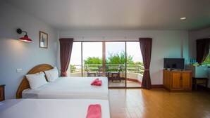 Habitación de hotel con dos camas, televisor, escritorio y balcón con mesa y sillas.