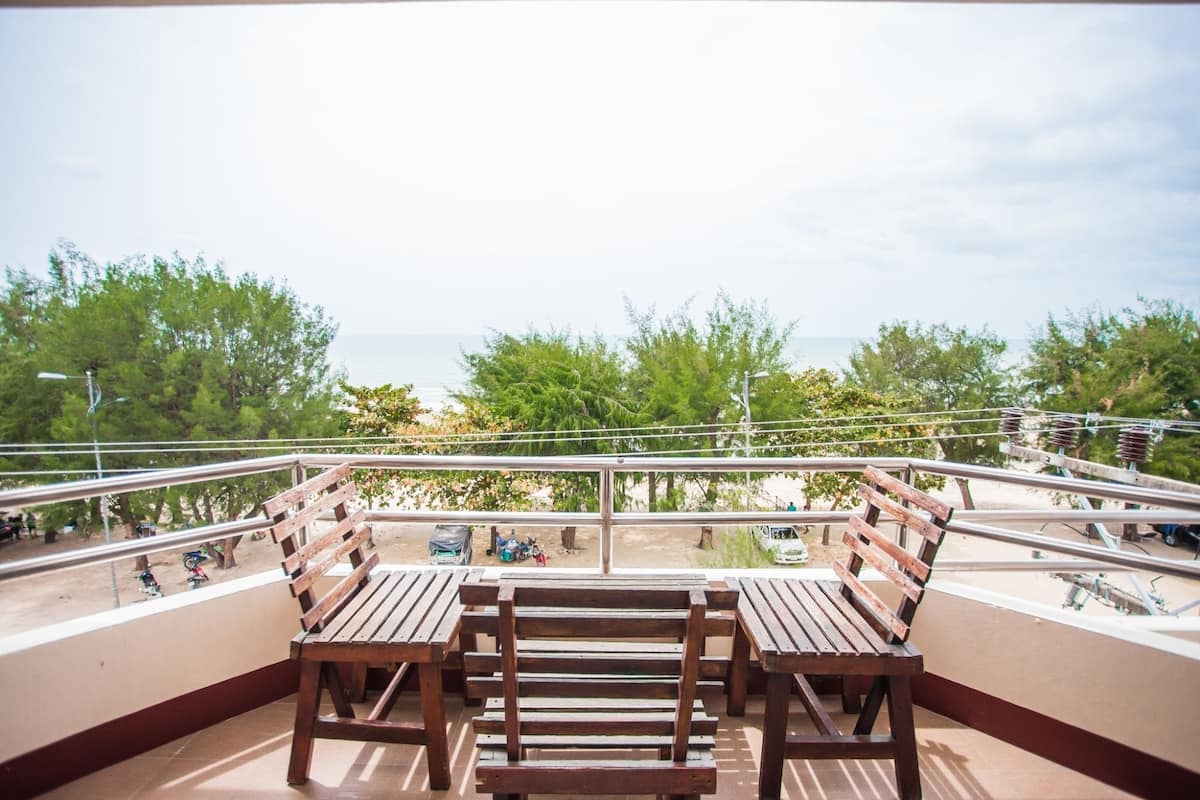 Een balkon met houten banken en uitzicht op zee.