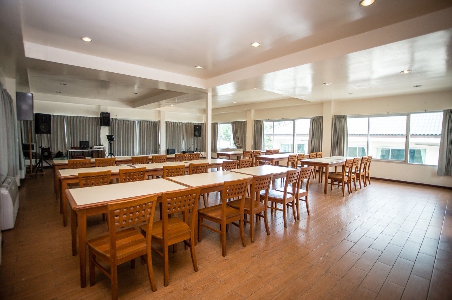 Une salle de conférence spacieuse, dotée de plusieurs tables et chaises, de grandes fenêtres et d’un éclairage au plafond.