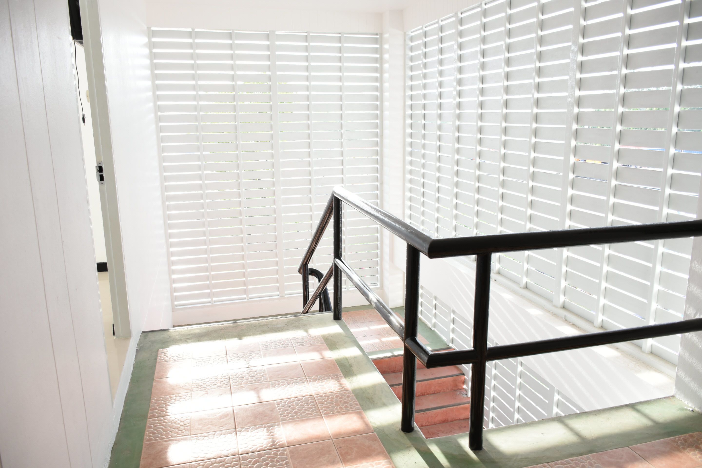A staircase with a metal handrail, white walls, and a tiled floor.
