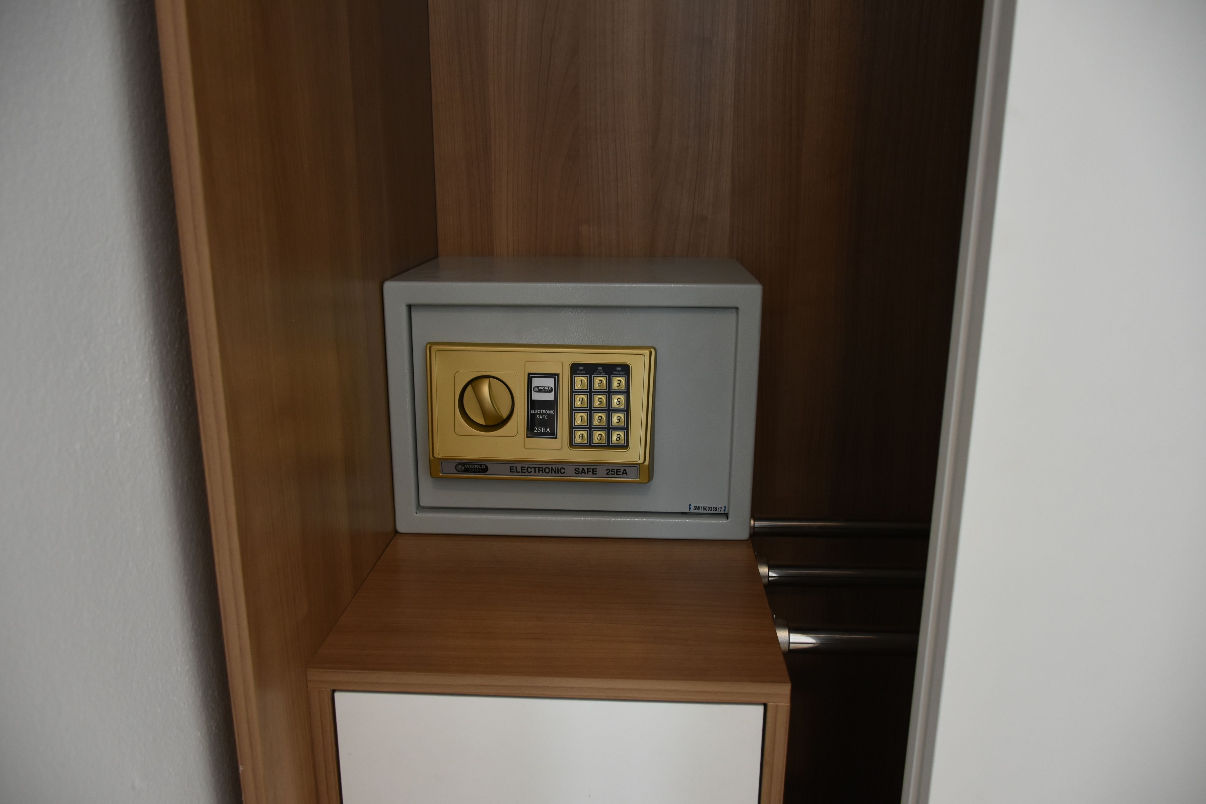 Una caja fuerte con teclado y cerradura de combinación, ubicada en un mueble de madera.
