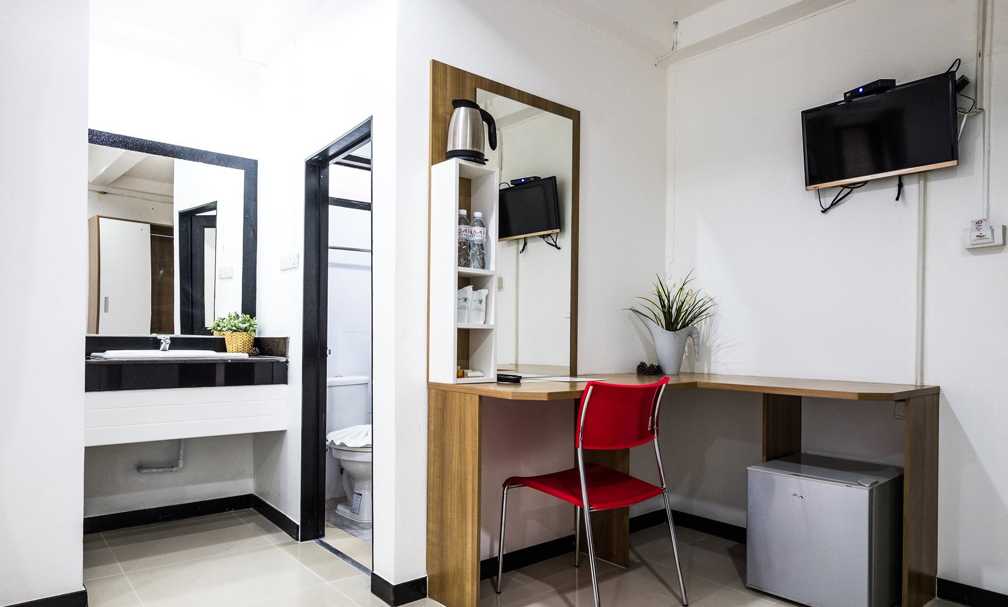 A modern bathroom with a mirror, sink, toilet, and a small refrigerator.