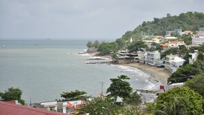 A coastal town with buildings along the beach, a lighthouse, and a ship in the distance. - Valley Mountain Hotel (Ho Chi Minh City)