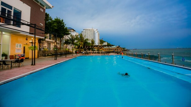A swimming pool with a view of the ocean and a building in the background. - Valley Mountain Hotel (Ho Chi Minh City)