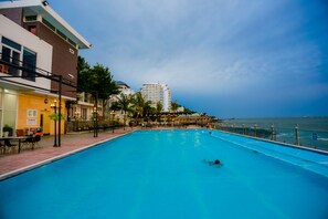 Una piscina con vista al océano y un edificio al fondo.