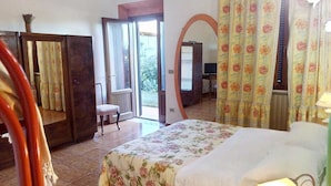 A bedroom with a bed, a chair, a mirror, and a door leading to a balcony. - Agriturismo Da Paola (Manciano)