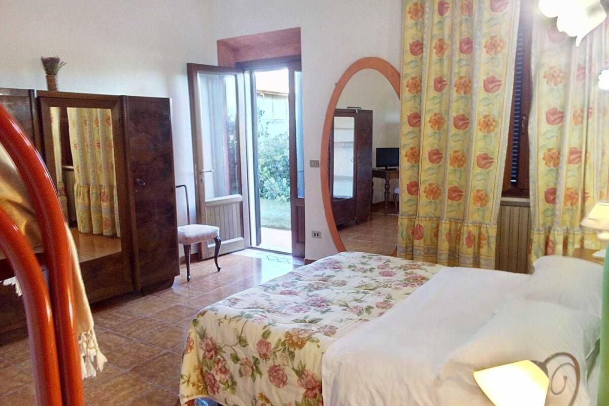 Un dormitorio con una cama, una silla, un espejo y una puerta que da a un balcón.
