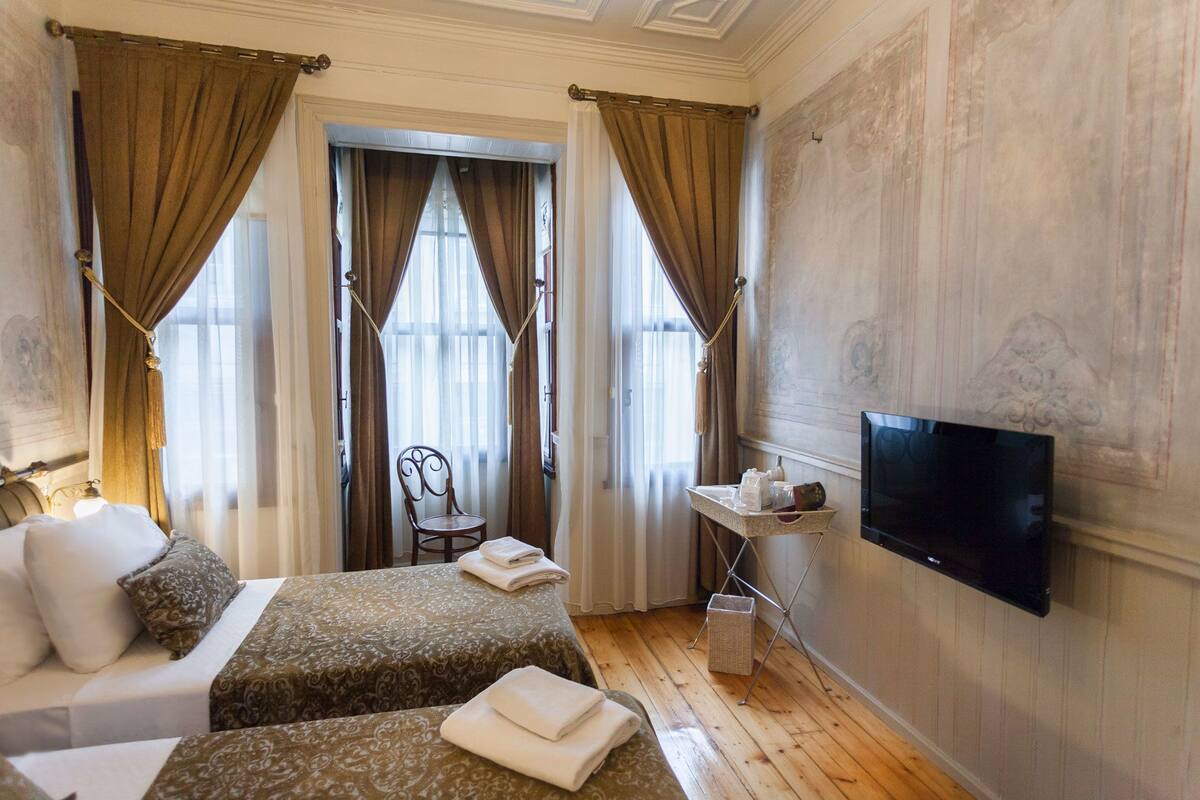 A hotel room with two beds, a television, and a chair.