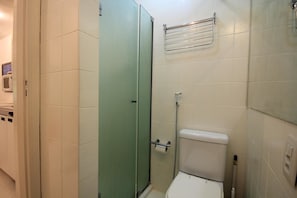 A bathroom with a toilet, a glass-enclosed shower, and a towel rack.