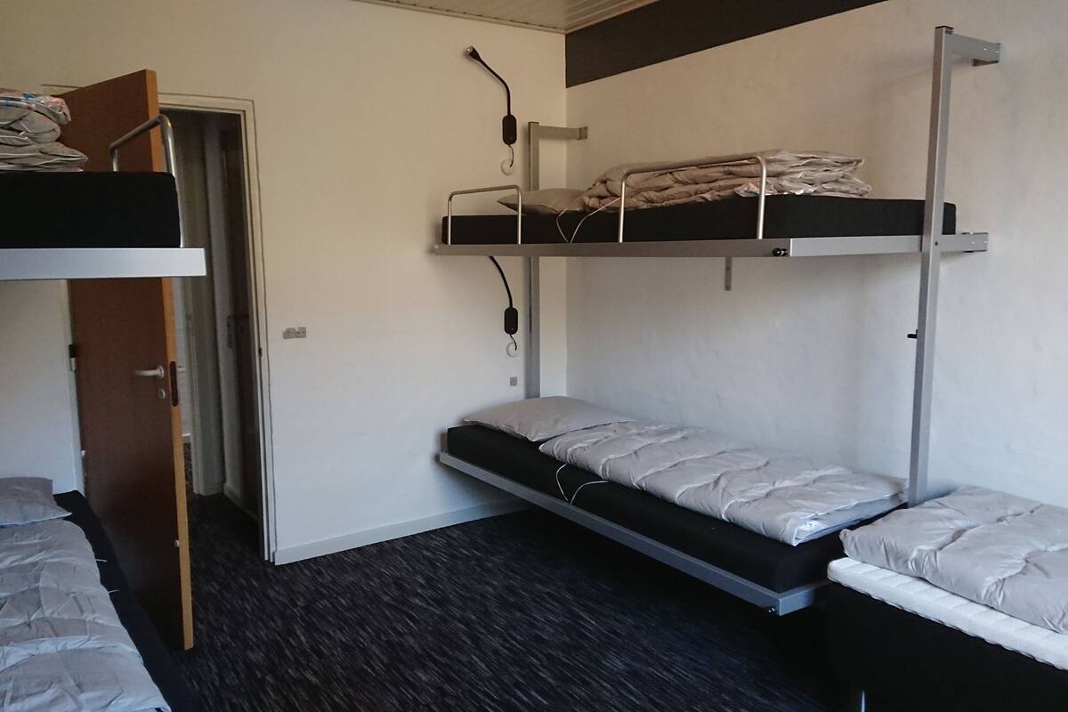 Een slaapzaal met twee stapelbedden, een deur en een klein bureau.