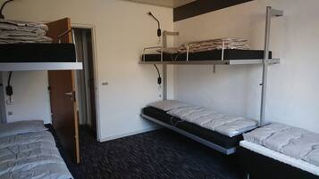 Un dormitorio con dos literas, una puerta y un escritorio pequeño.