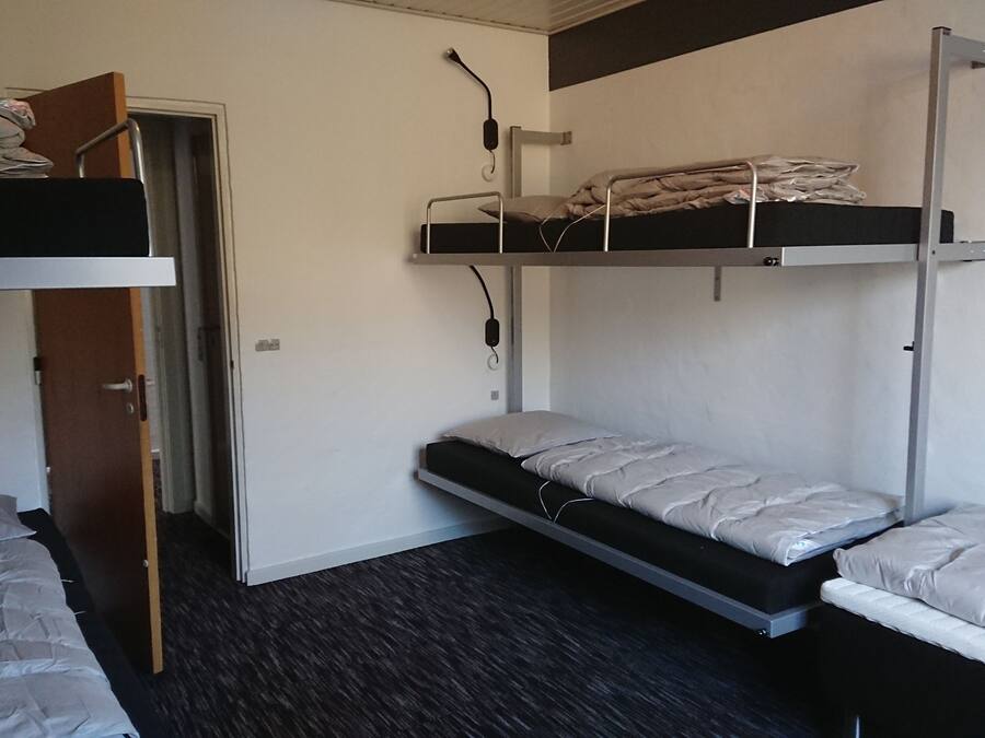 Un dormitorio con dos literas, una puerta y un escritorio pequeño.