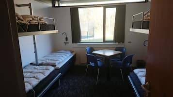 Habitación pequeña con literas, una mesita y sillas.
