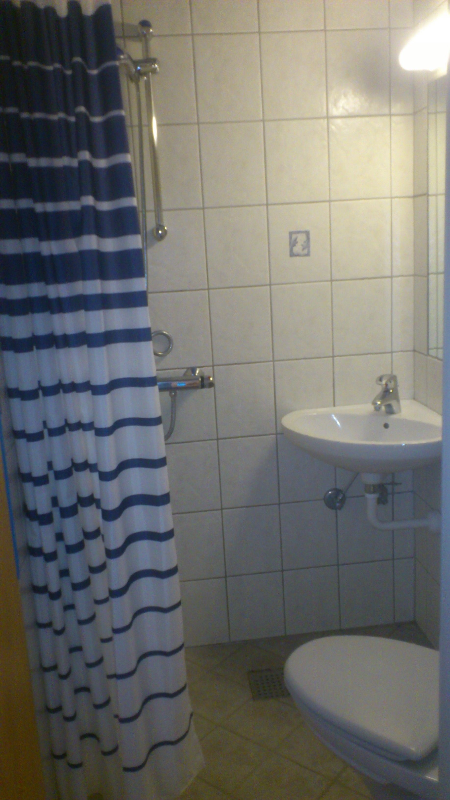 Un baño con ducha, lavamanos e inodoro.